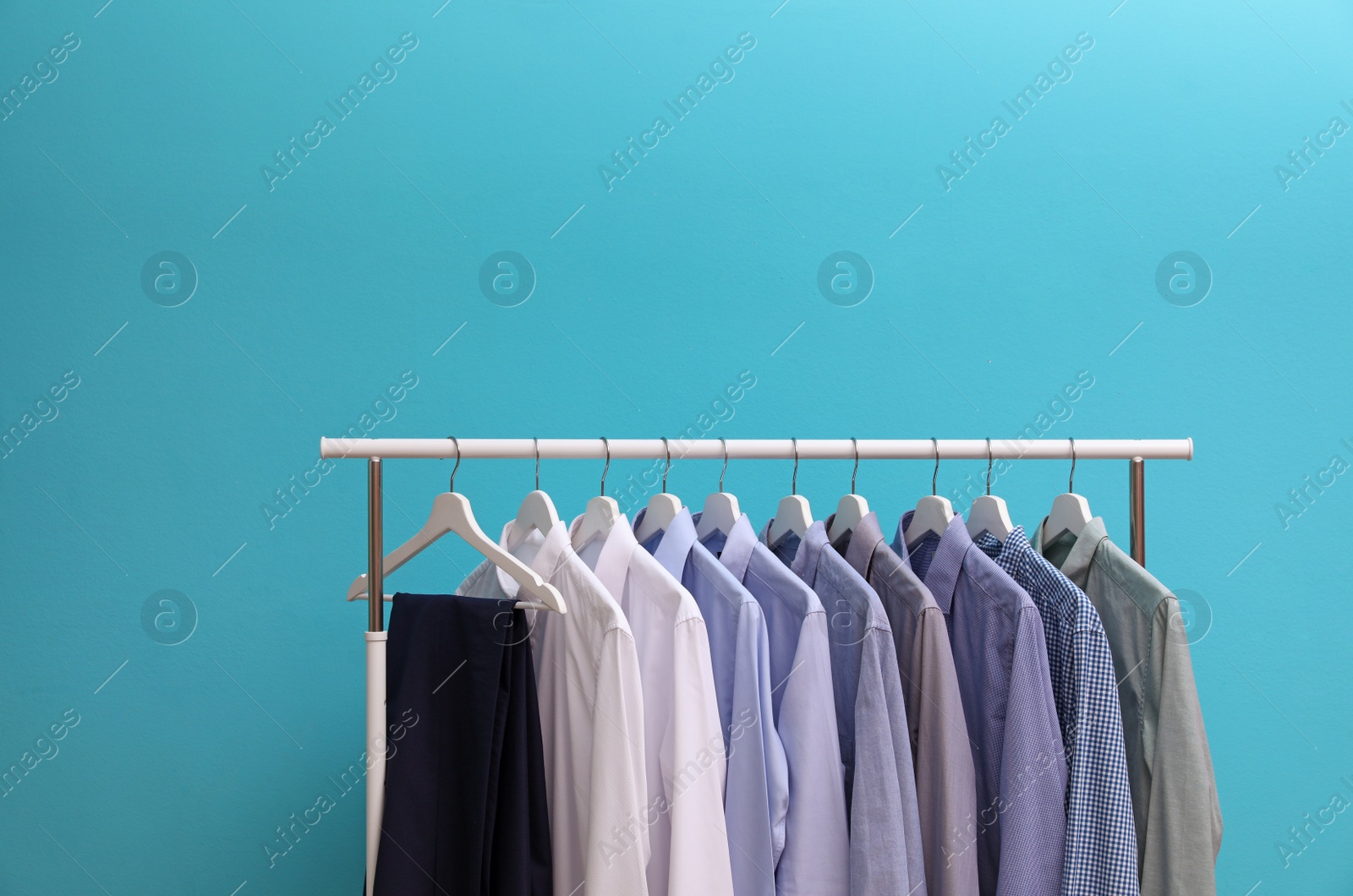 Photo of Wardrobe rack with men's clothes on color background. Space for text