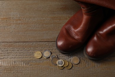 Poverty. Old boots and coins on wooden table, top view. Space for text