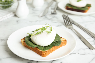 Photo of Delicious poached egg sandwich served on white marble table