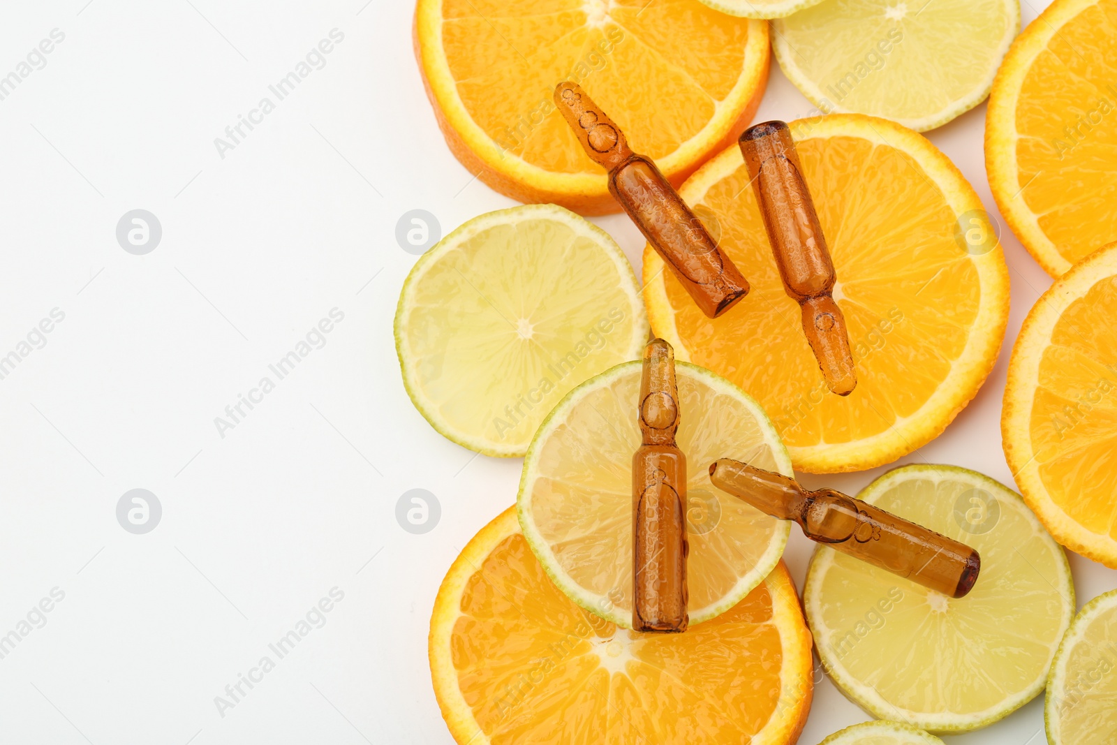 Photo of Skincare ampoules with vitamin C, lemon and orange slices on white background, flat lay. Space for text