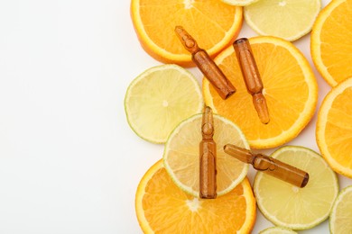 Photo of Skincare ampoules with vitamin C, lemon and orange slices on white background, flat lay. Space for text