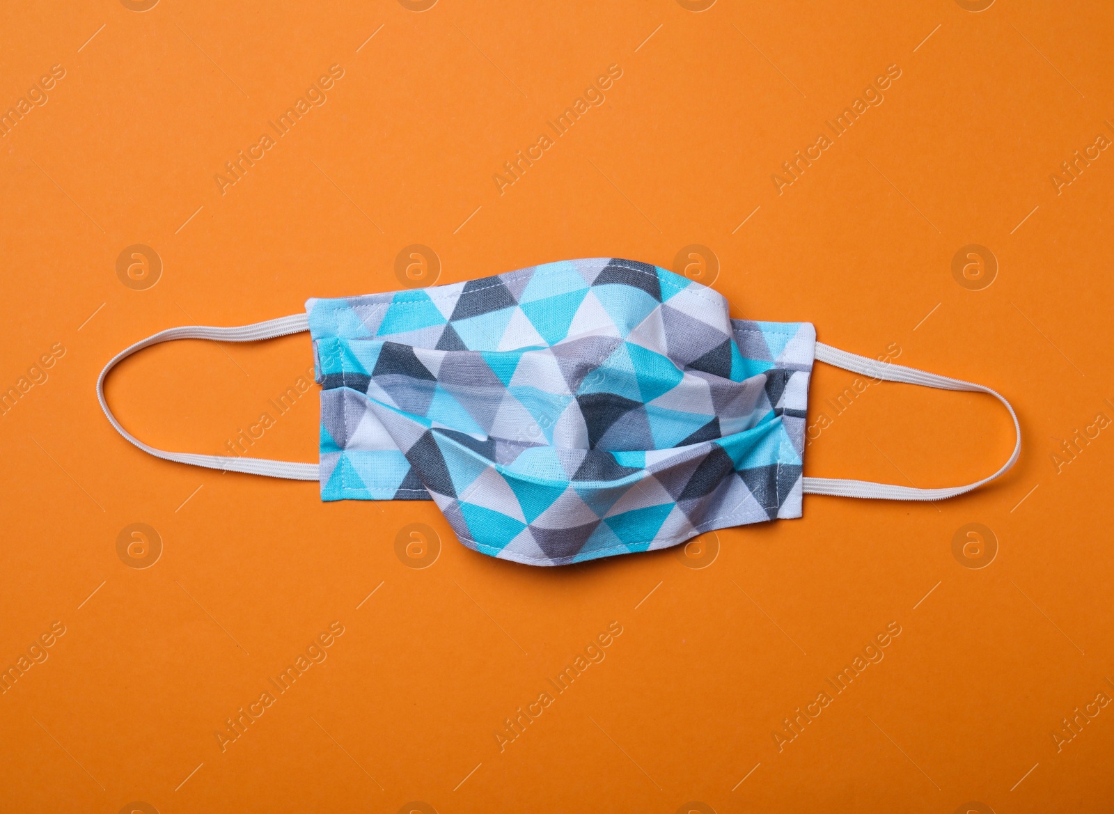 Photo of Homemade protective mask on orange background, top view. Sewing idea