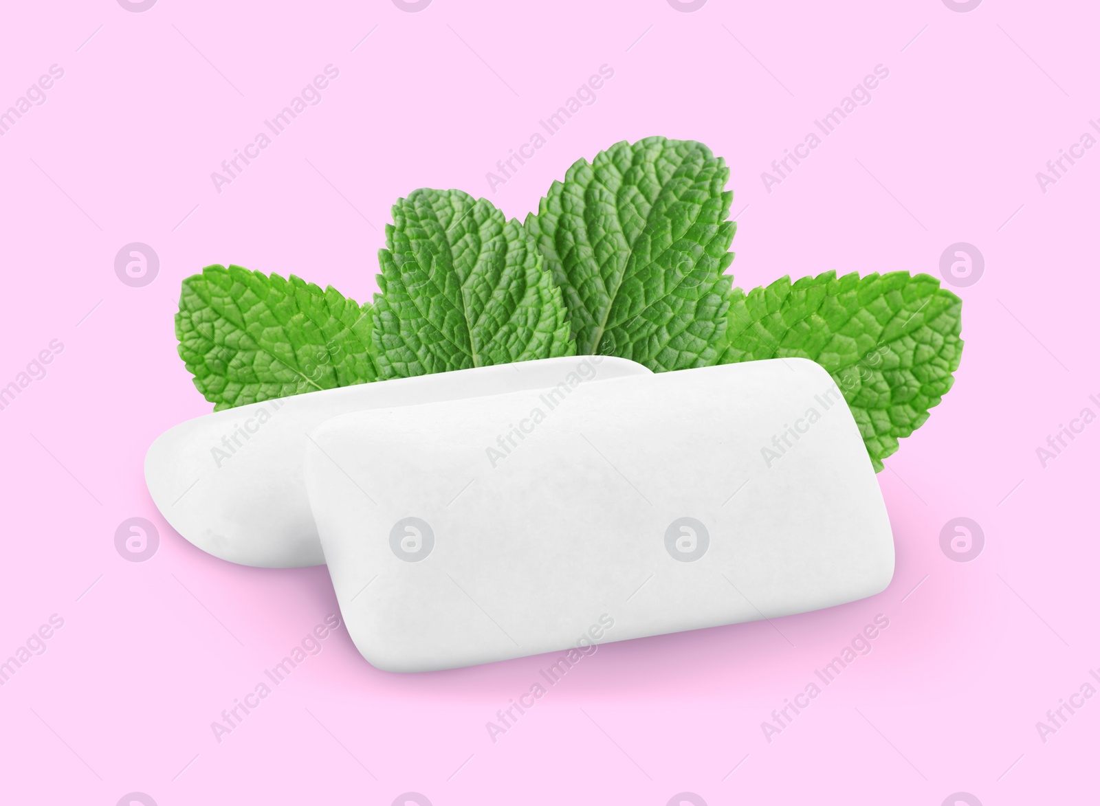 Image of Menthol chewing gum pillows and mint leaves on light pink background