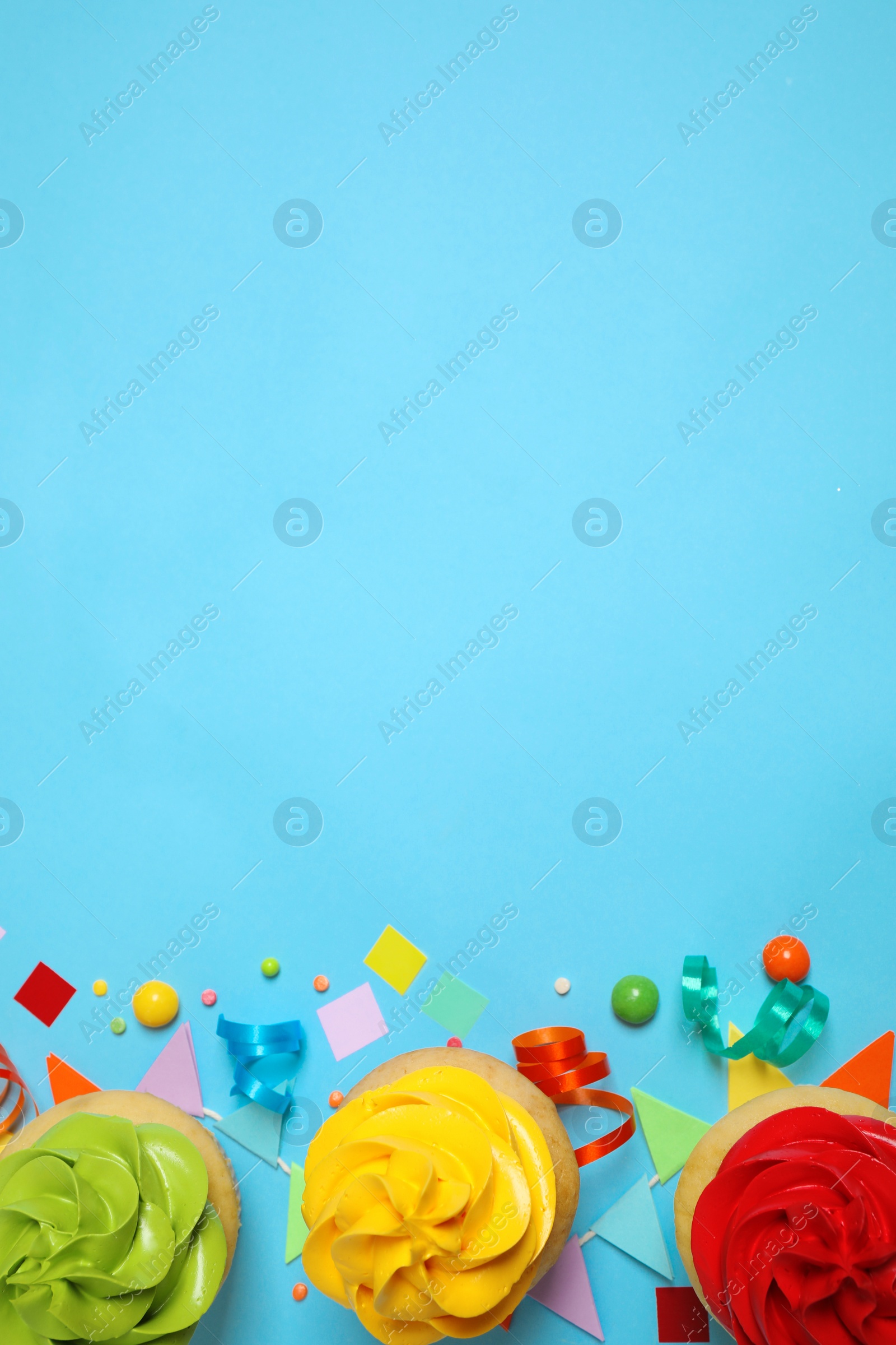 Photo of Colorful birthday cupcakes on light blue background, flat lay. Space for text