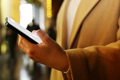 Woman using smartphone on night city street, closeup