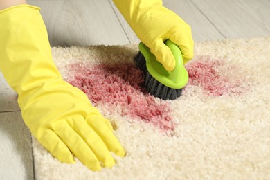 Photo of Woman removing stain from beige carpet, closeup