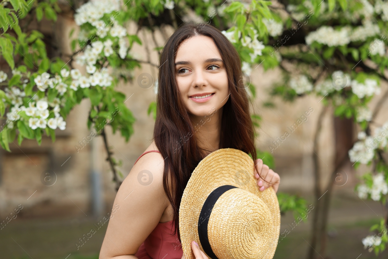 Photo of Beautiful woman with straw hat near blossoming tree on spring day