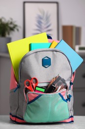 Children's backpack with different school stationery on table indoors