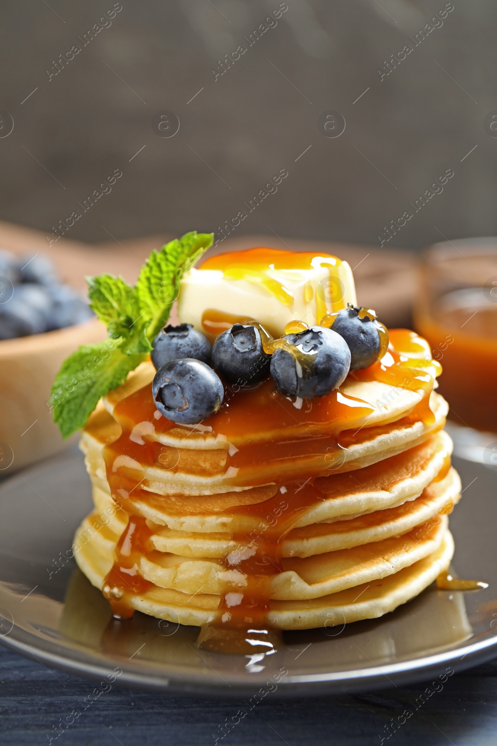Photo of Delicious pancakes with fresh blueberries, butter and syrup on table