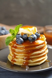 Delicious pancakes with fresh blueberries, butter and syrup on table