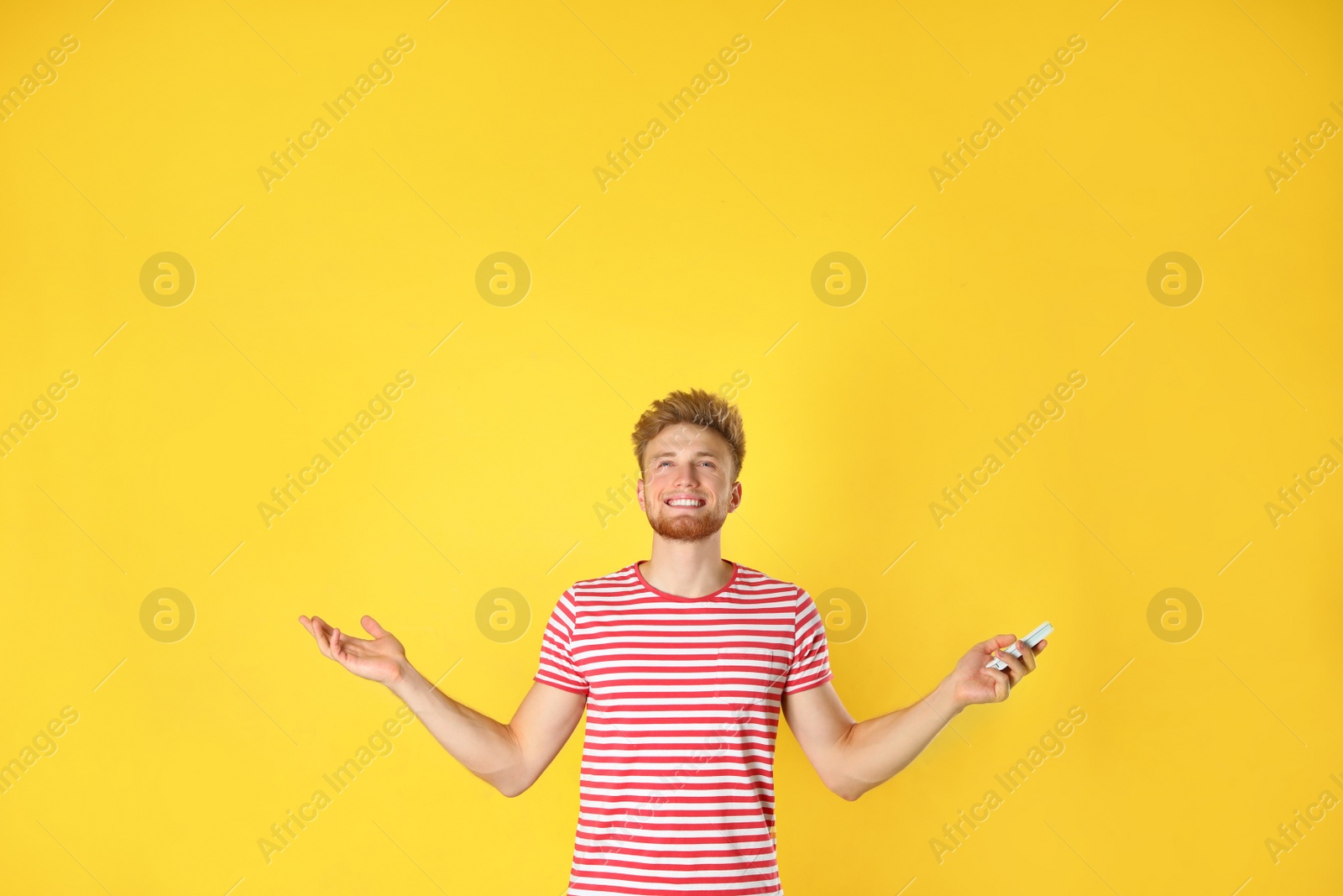 Photo of Young man with air conditioner remote on yellow background