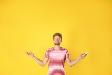 Photo of Young man with air conditioner remote on yellow background