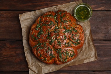 Photo of Traditional Ukrainian garlic bread with herbs (Pampushky) and aromatic oil on wooden table, flat lay