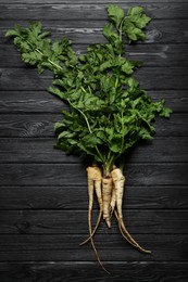 Photo of Tasty fresh ripe parsnips on black wooden table, flat lay