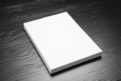 Photo of Stack of blank paper sheets for brochure on black wooden background. Mock up