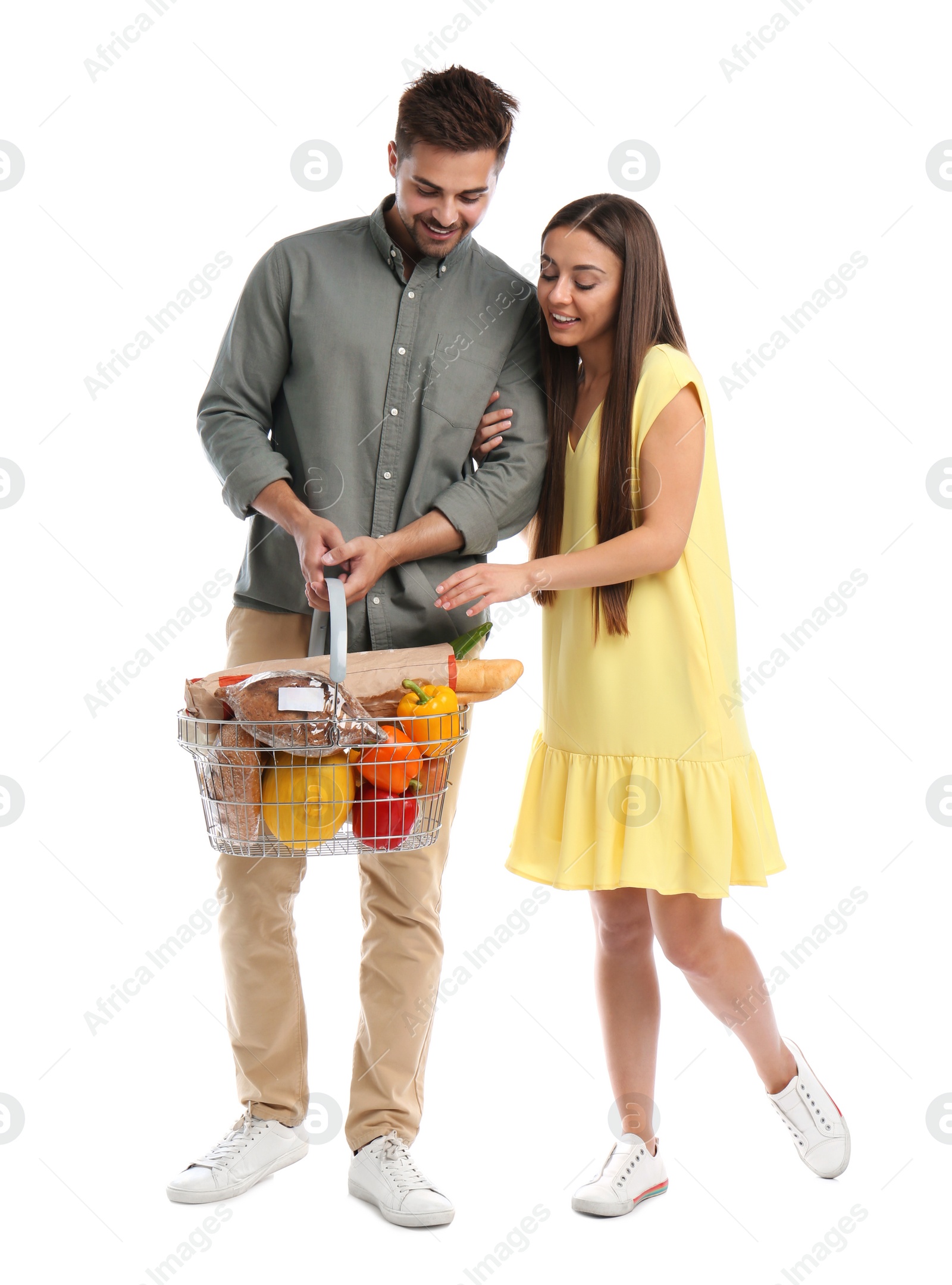 Photo of Young couple with shopping basket full of products isolated on white