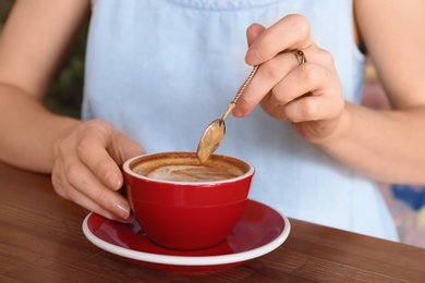 Woman with cup of fresh aromatic coffee at table, closeup