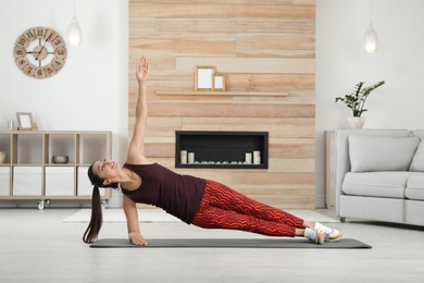 Young woman in fitness clothes doing exercise at home