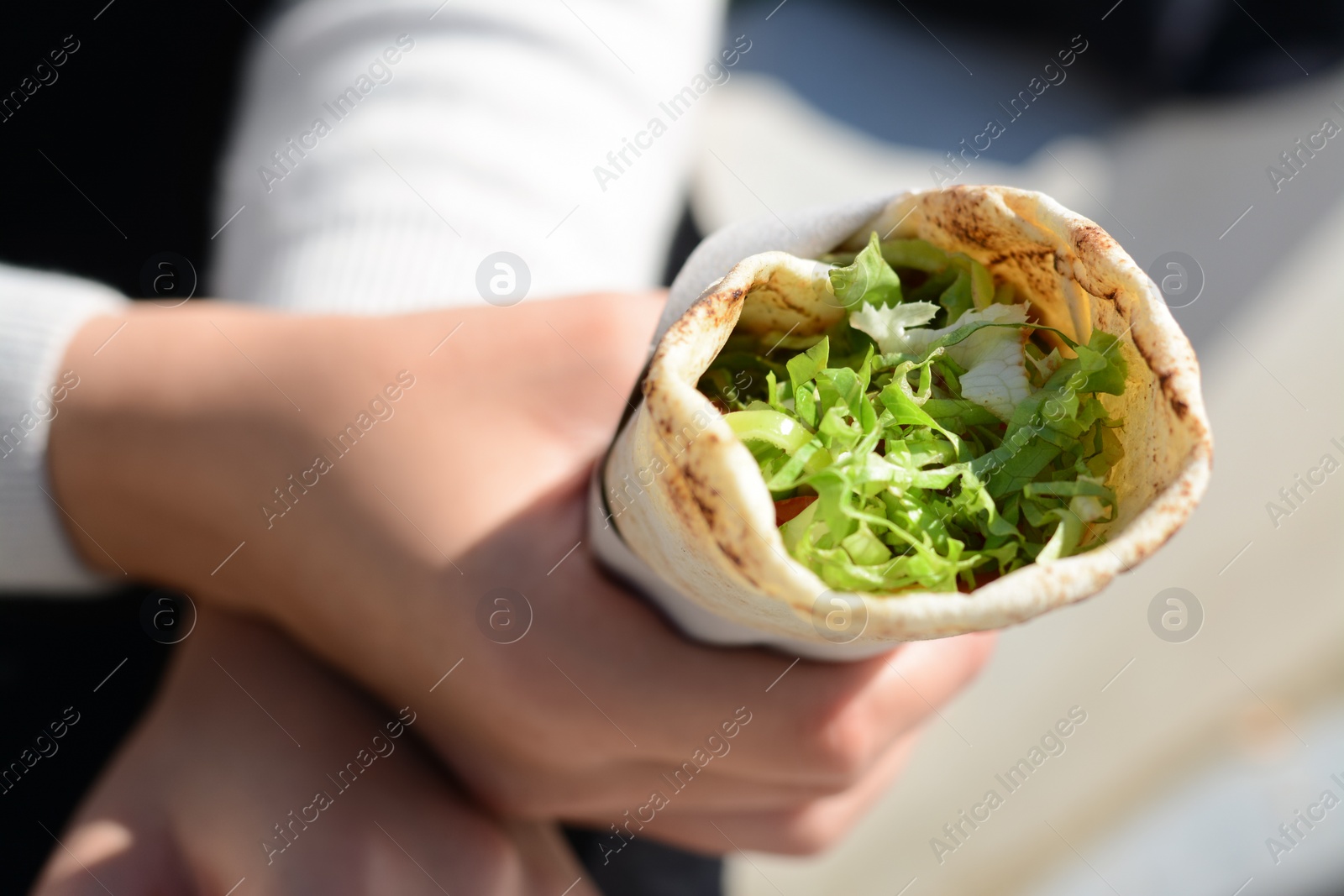 Photo of Woman holding delicious vegetable roll outdoors, closeup