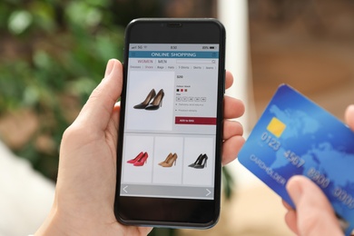 Photo of Woman with credit card using smartphone for online shopping indoors, closeup