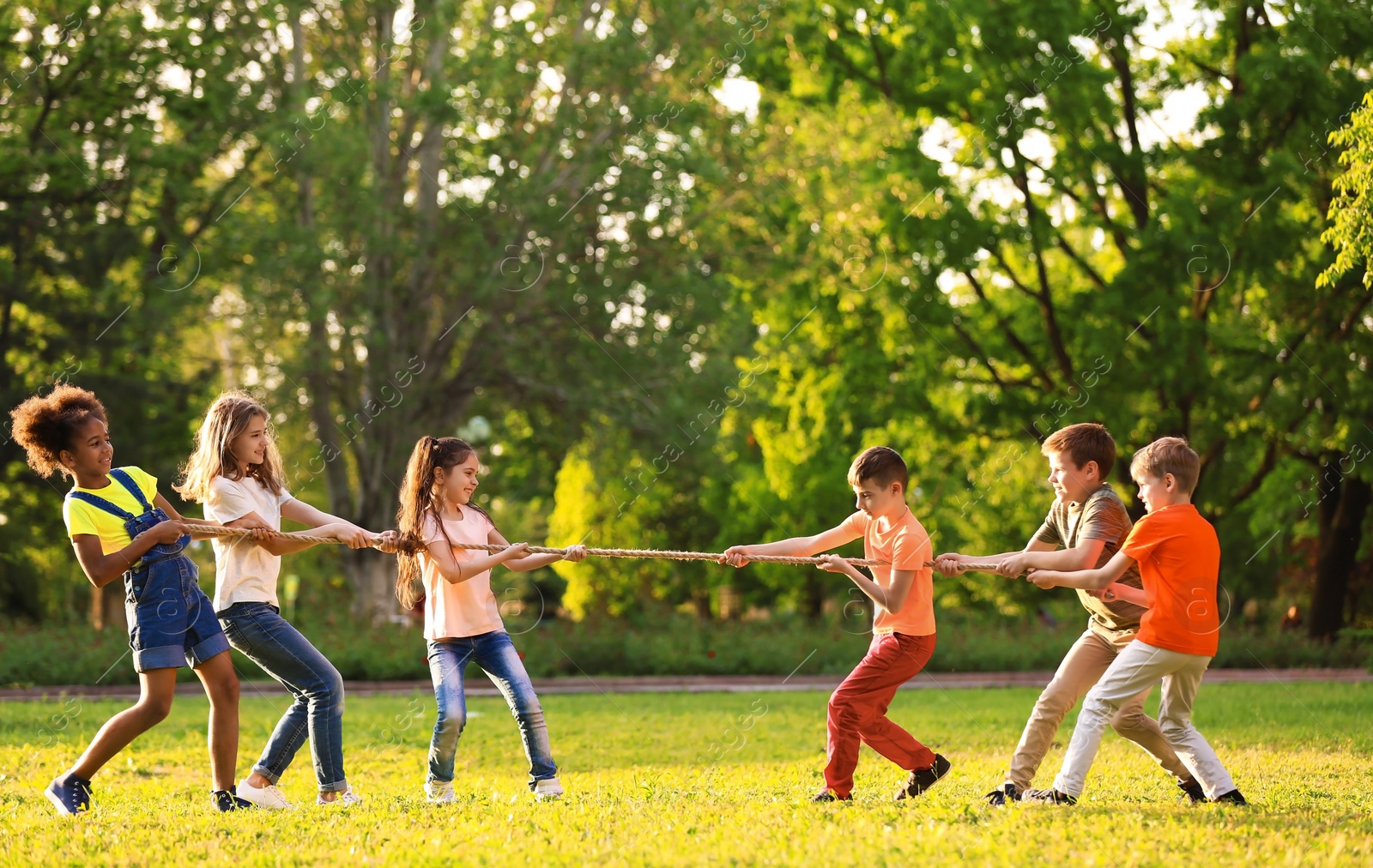 Photo of Cute little children playing with rope outdoors on sunny day