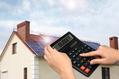 Image of Budget plan. Woman using calculator near house outdoors, closeup