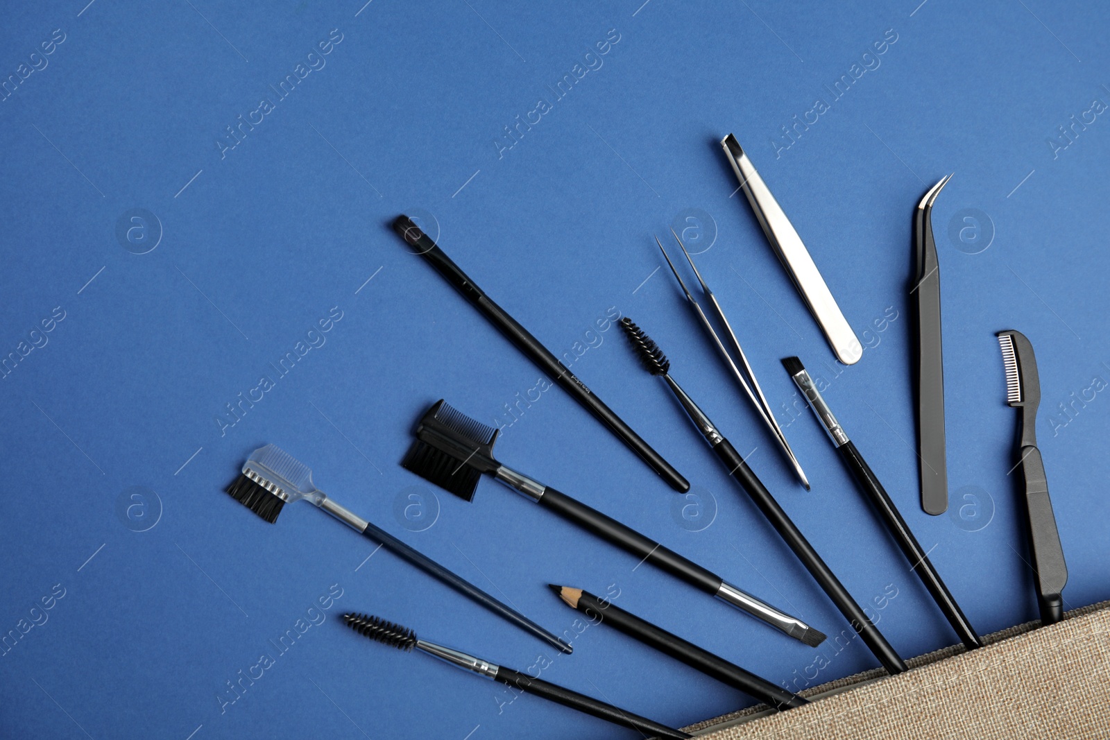 Photo of Set of professional eyebrow tools on blue background, flat lay