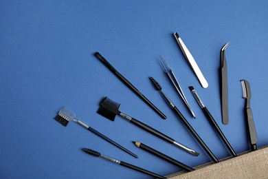 Set of professional eyebrow tools on blue background, flat lay