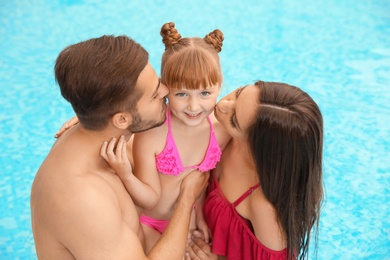Photo of Parents kissing their daughter in swimming pool