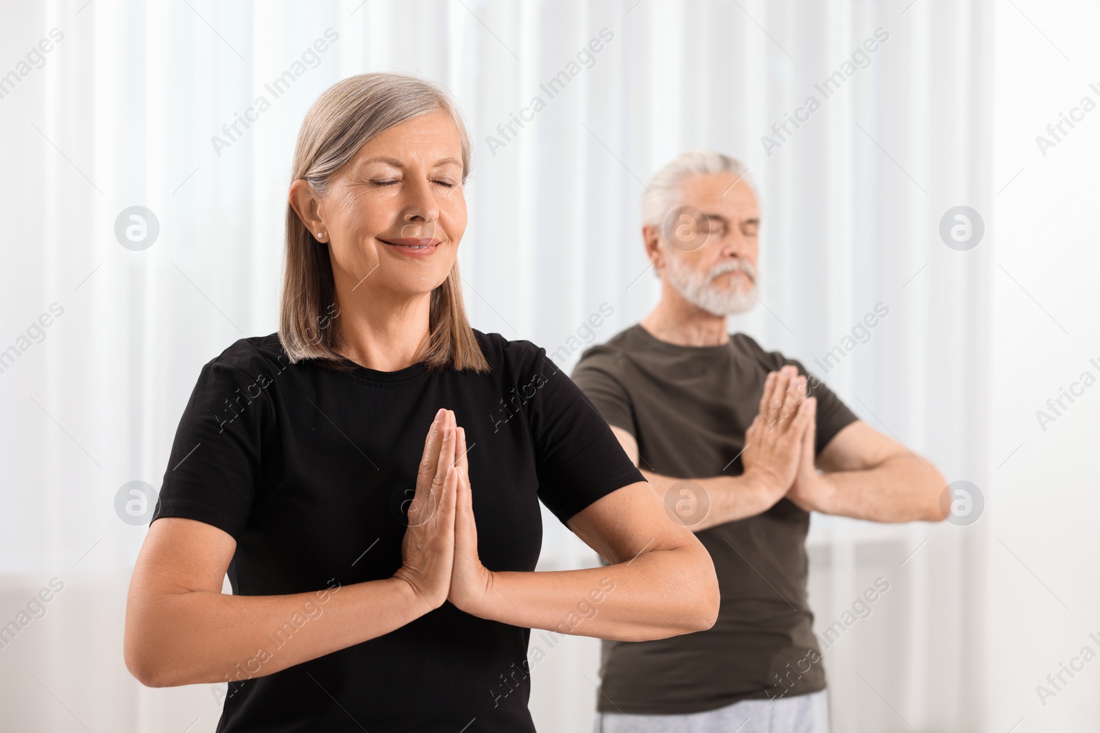 Photo of Senior couple practicing yoga indoors, selective focus