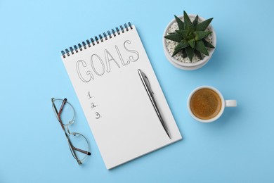 Photo of Planning concept. Flat lay composition with empty list of goals in notebook and glasses on light blue background