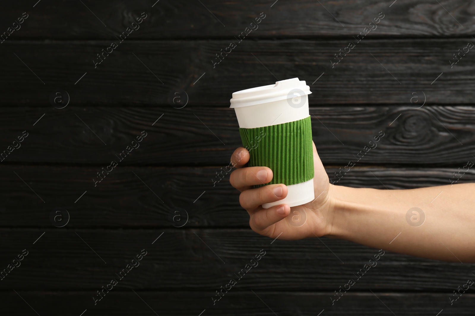 Photo of Woman holding takeaway paper coffee cup on wooden background. Space for text