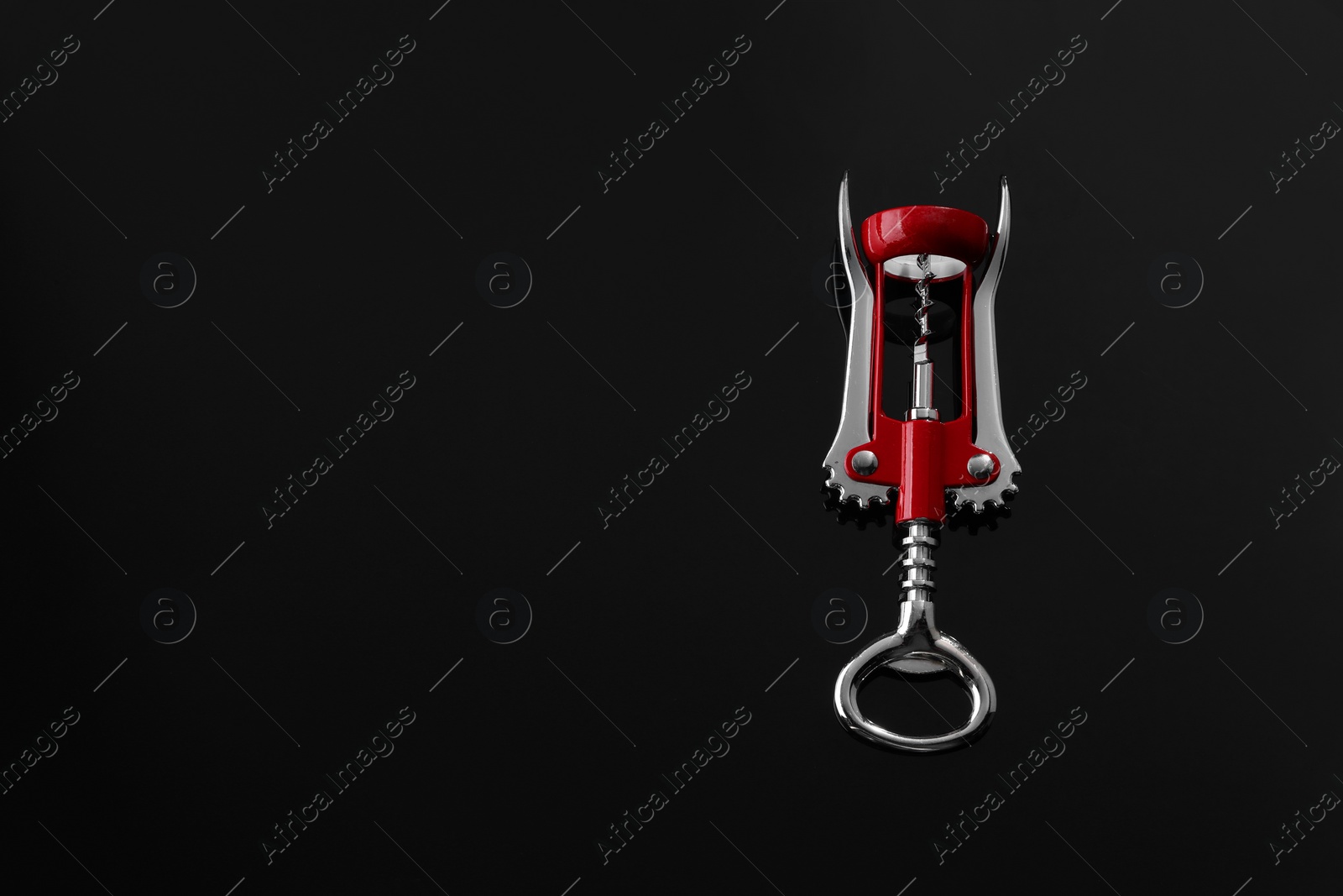 Photo of One wing corkscrew on black table, top view. Space for text