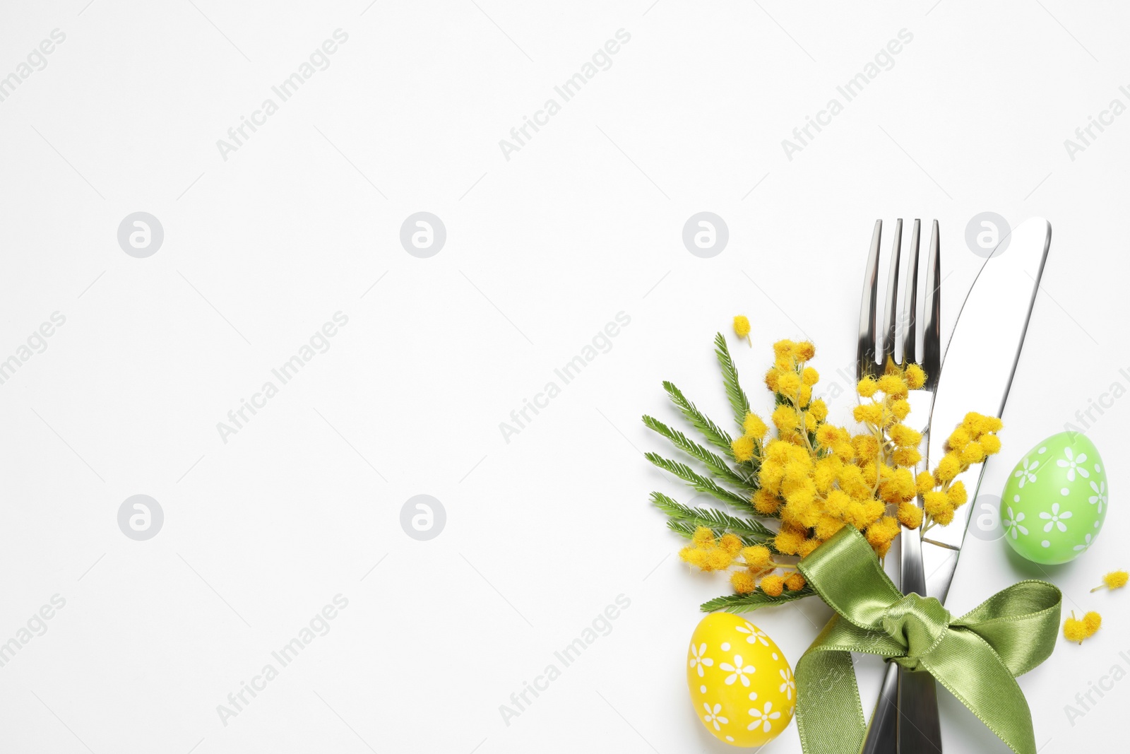 Photo of Top view of cutlery set with floral decor for Easter celebration on white background