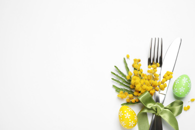 Top view of cutlery set with floral decor for Easter celebration on white background