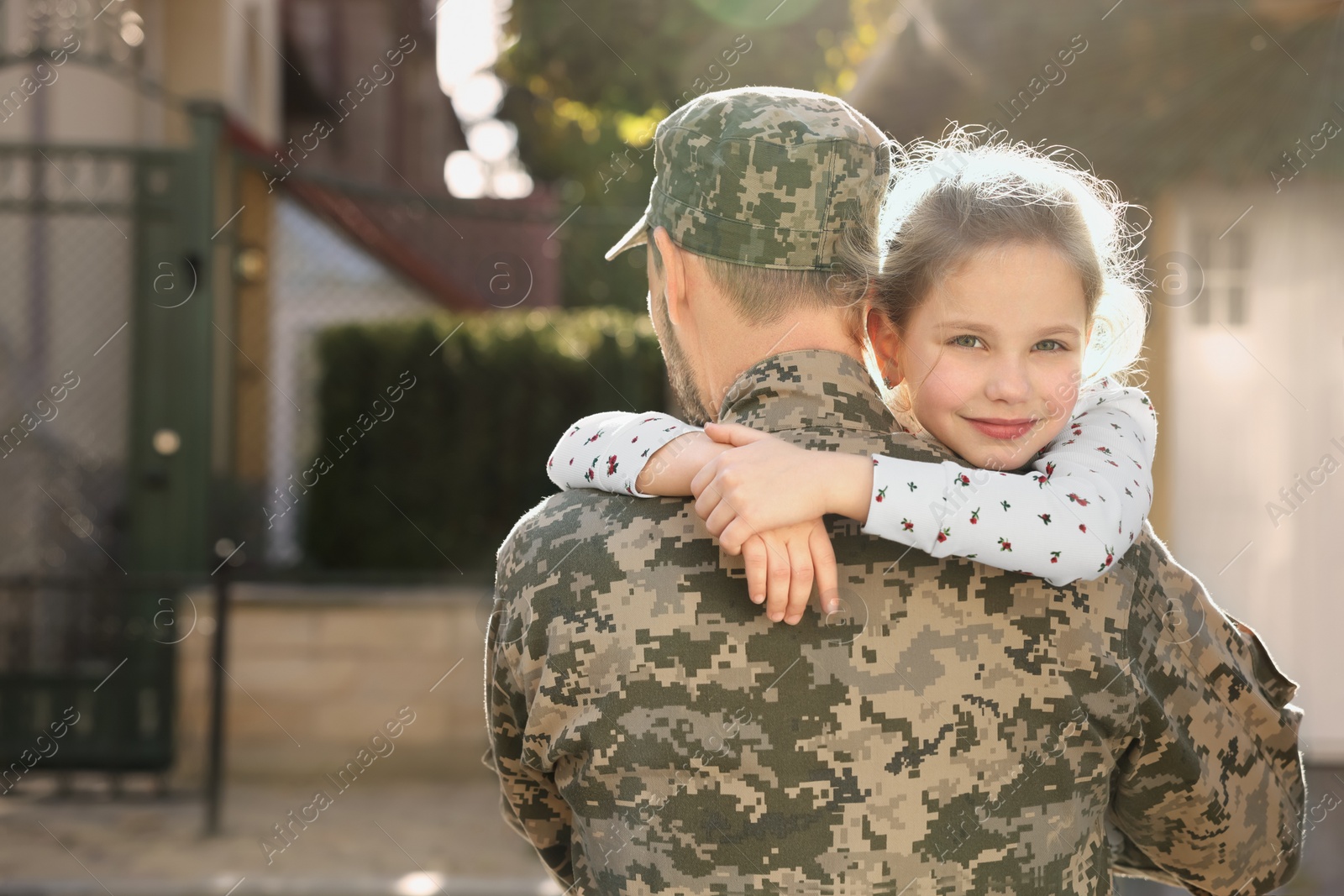 Photo of Soldier in Ukrainian military uniform hugging his daughter outdoors, space for text. Family reunion