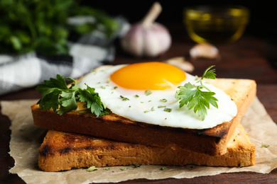 Photo of Tasty fried egg with toasts and parsley on wooden table, closeup