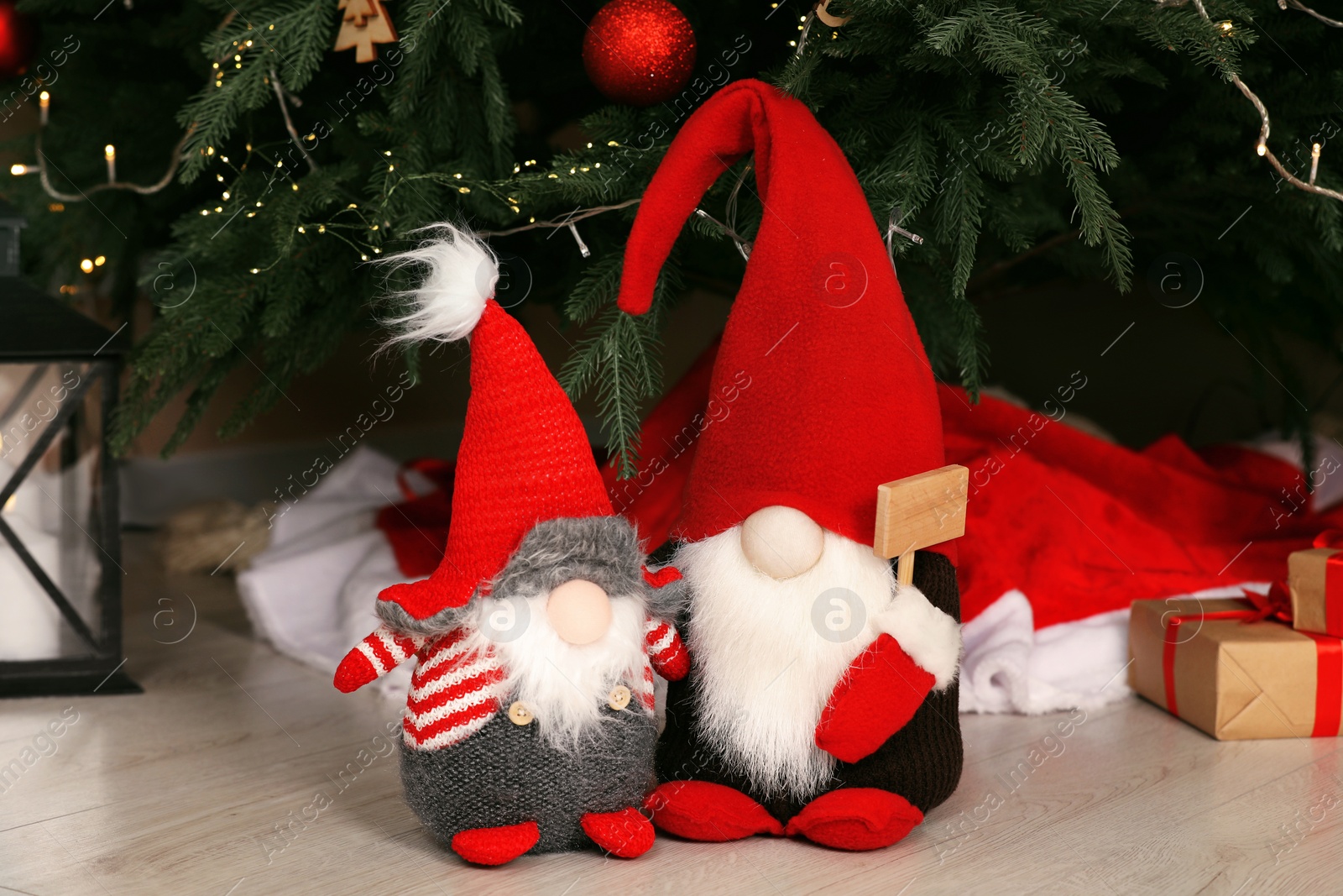 Photo of Cute decorative gnomes on floor near Christmas tree at home