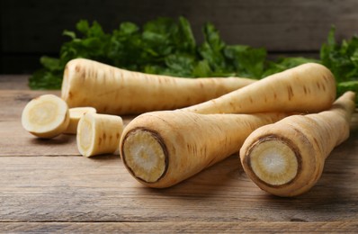Photo of Many fresh ripe parsnips on wooden table, closeup