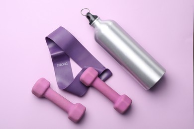 Photo of Two dumbbells, fitness elastic band and thermo bottle on violet background, flat lay