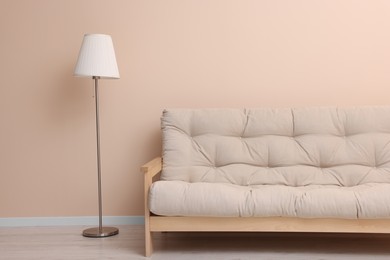 Photo of Comfortable sofa and stylish lamp near beige wall indoors