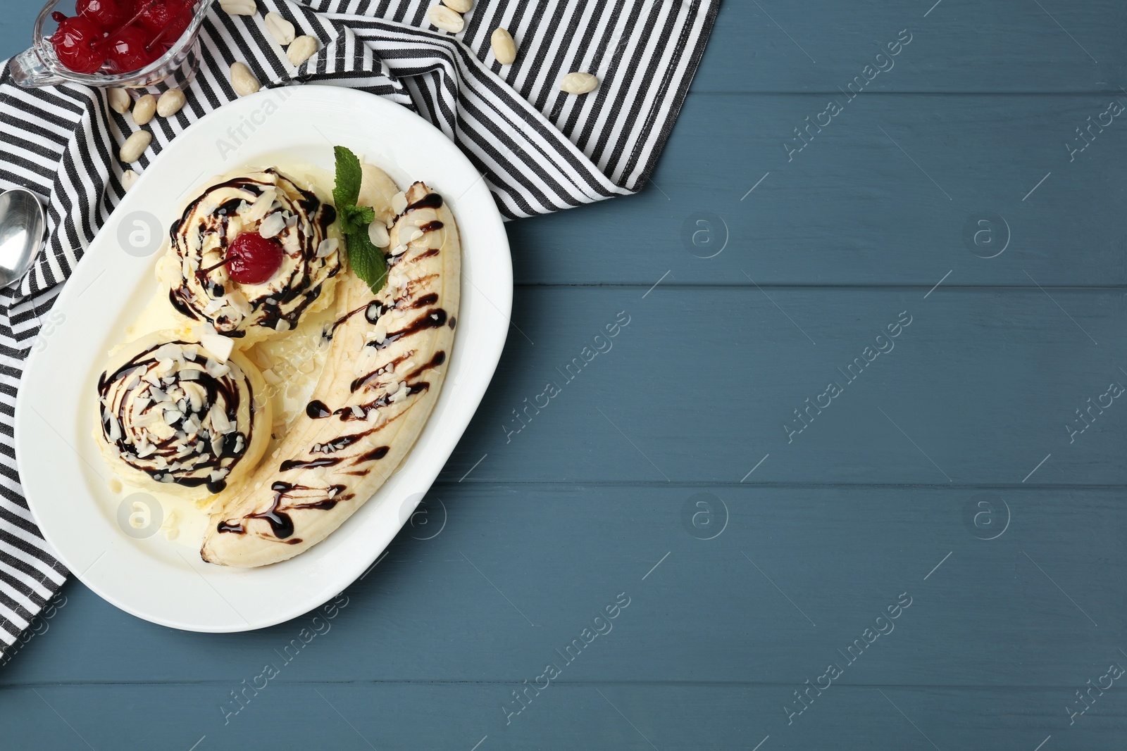 Photo of Delicious dessert with banana ice cream on blue wooden table, flat lay. Space for text