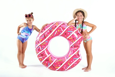 Cute little children in beachwear with bright inflatable ring on white background