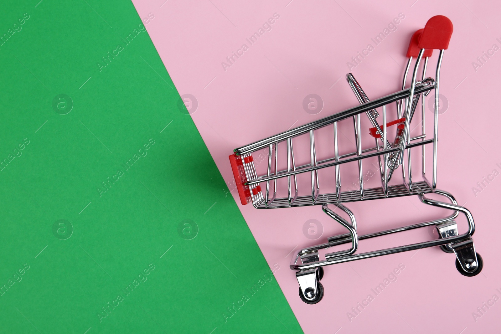 Photo of Empty shopping trolley on color background, top view. Space for text