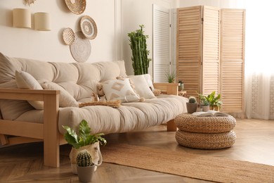 Stylish living room interior with comfortable wooden sofa and beautiful houseplants