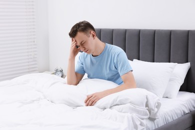 Sad man suffering from headache in bed indoors