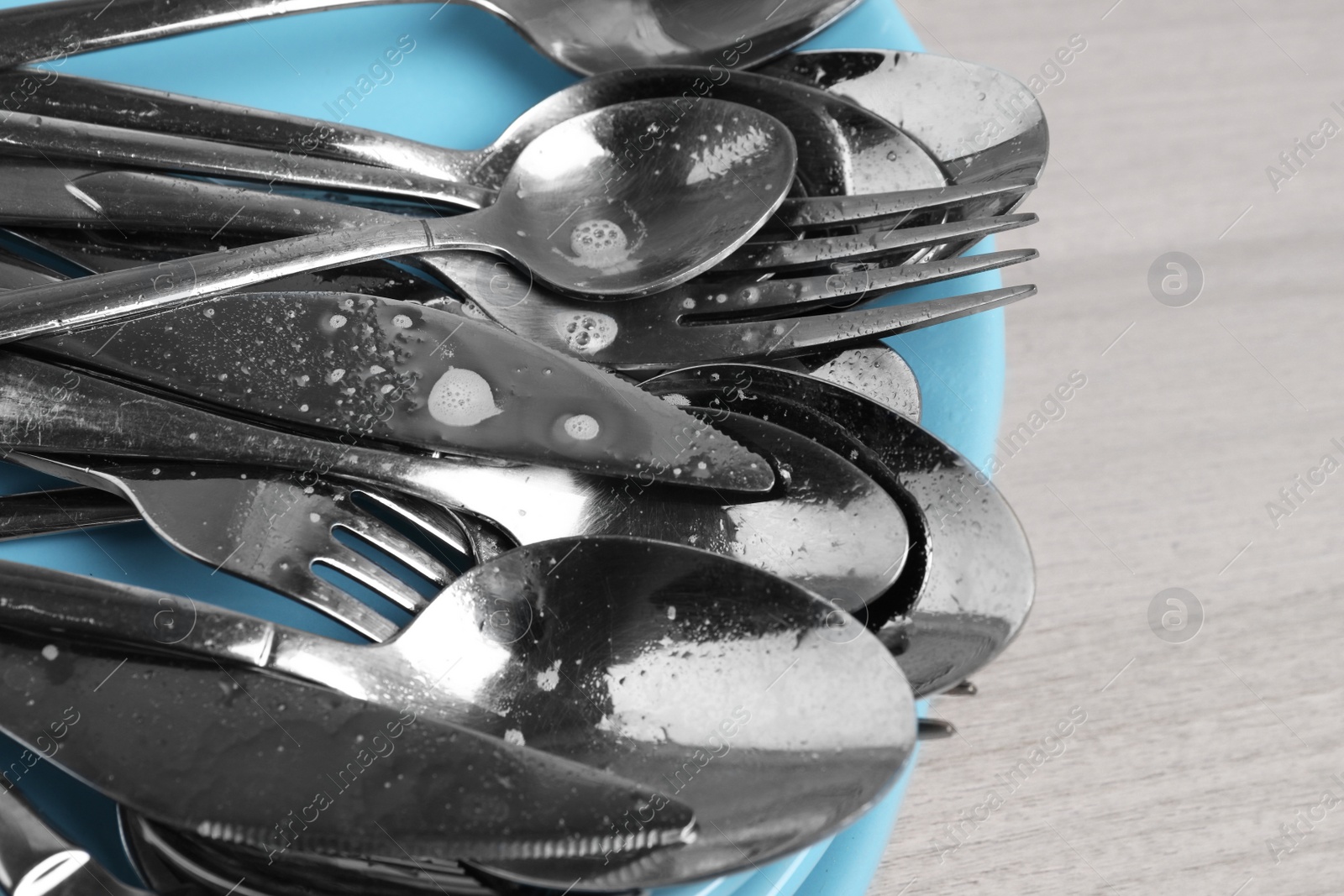 Photo of Silver clean spoons, forks and knives on white wooden table, closeup