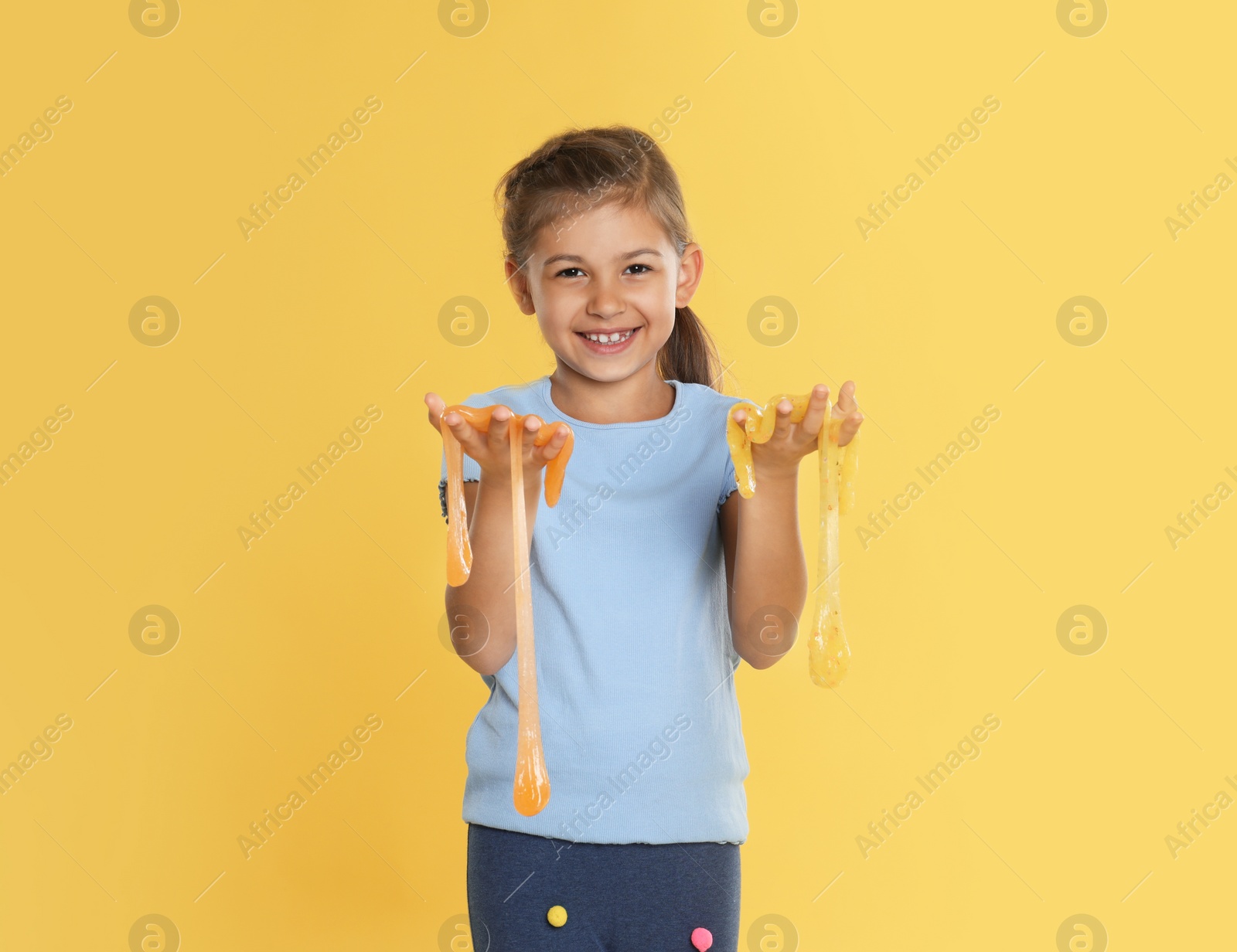 Photo of Little girl with slime on yellow background