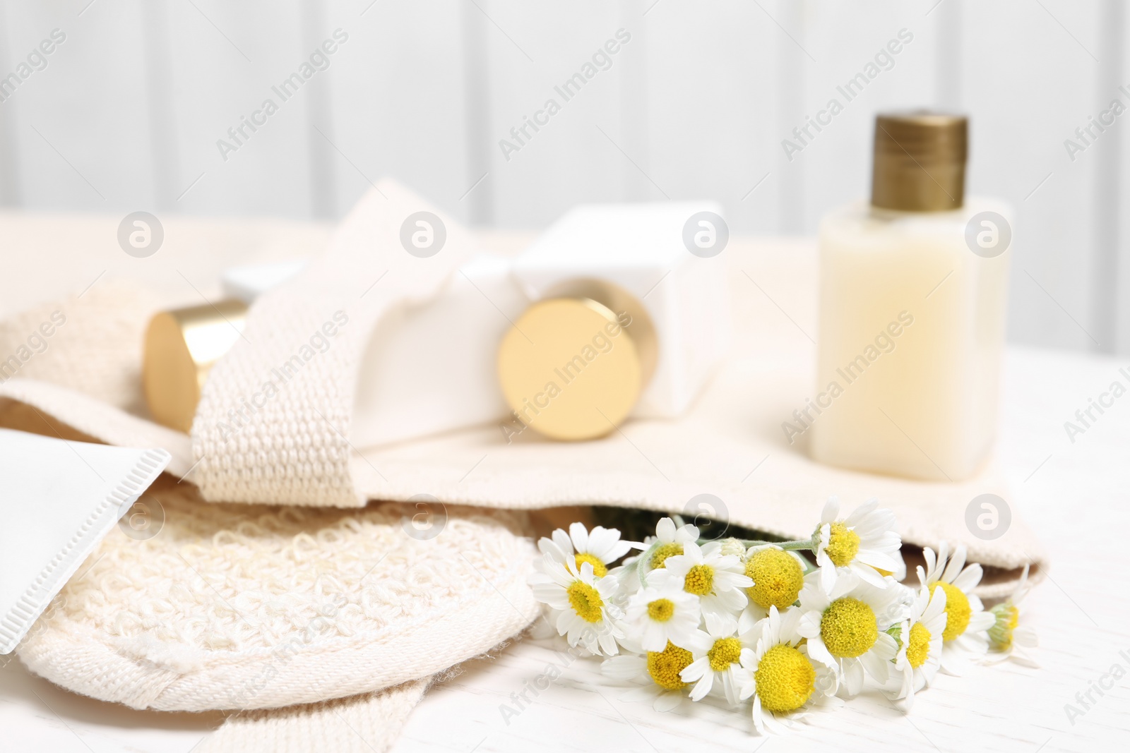Photo of Chamomile flowers and loofah on white table, closeup