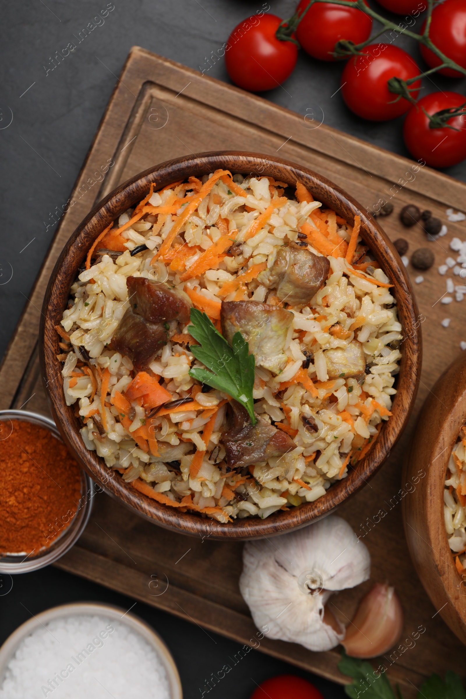 Photo of Delicious pilaf and products on black table, flat lay